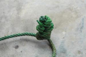 Green knotted rope isolated with whitish gray wall photo