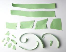 various torn strips of green paper on a white background photo