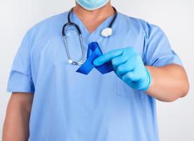doctor in blue uniform and sterile latex gloves holds a dark blue ribbon photo