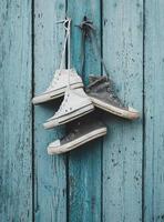two pairs of old worn textile sneakers hang on a nail photo