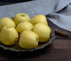 ripe fresh yellow apples on a brown wooden table photo