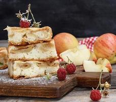 pieces of apple pie are stacked on a brown wooden board photo