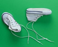 par de viejas zapatillas textiles blancas con cordones desatados foto