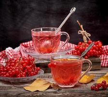 viburnum tea in a transparent cup with a handle and saucer on a gray wooden table photo