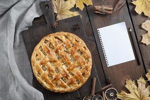 baked whole round apple pie on a brown wooden board, puff pastry photo