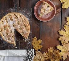 baked round apple pie and one cut piece on a plate photo
