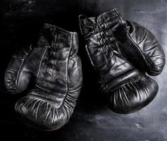 pair of old leather boxing gloves with laces on a wooden background photo