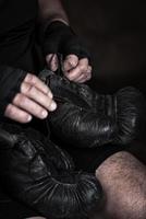 athlete puts on black leather boxing gloves photo