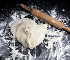 white wheat flour dough and wooden rolling pin photo