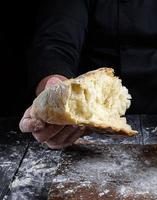 male chef hand holds half baked white wheat flour bread photo