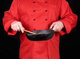 cook in red uniform holding an empty black frying pan photo