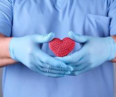 médico con azul látex guantes participación un rojo corazón foto
