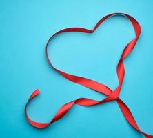 red silk ribbon on a blue background, heart-shaped pattern photo