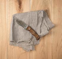kitchen knife on a gray napkin, wooden background photo