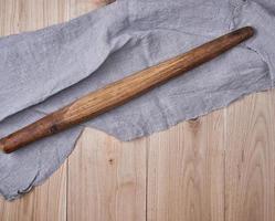 very old wooden rolling pin and a gray textile towel photo
