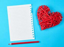 wooden wicker red heart and an empty white sheet of notepad photo