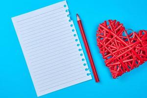 white piece of paper in a line and a red wooden pencil photo