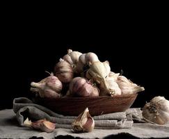 raw unpeeled garlic in a brown ceramic plate on a gray linen napkin photo