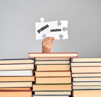 female hands holding big white puzzles over a stack of books photo