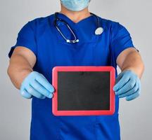 doctor in uniform and latex sterile gloves holding a blank black frame photo