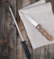 old sharp knife and sharpener with a handle on a gray wooden background photo