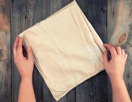 folded beige textile kitchen towel and two hands photo