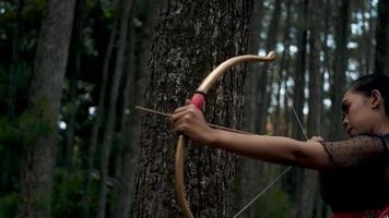 portrait tirer de femelle tournage un La Flèche de le arc dans le forêt