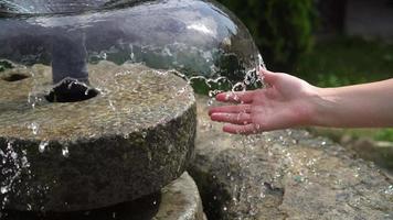 A woman's hand in the spray of water in the fountain video
