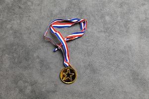 Simply flat lay design winner or champion gold trophy medal on concrete stone grey background. Victory first place of competition. Winning or success concept. Top view flat lay copy space. photo