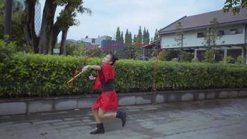 A Chinese Kids in a red costume having fun while playing with the rope video