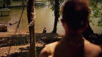 asiático hombre acecho un mujer jugando con el agua en un lago mientras meditando en el Roca video