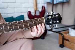 Closeup of woman playing guitar at home photo