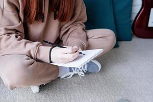 Young woman learning to play guitar at home photo