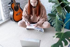 Young woman learning to play guitar at home photo