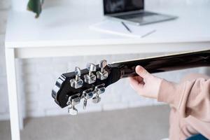 joven mujer aprendizaje a jugar guitarra a hogar foto