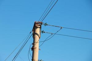 Electric pole with a linear wire against the blue sky close-up. Power electric pole. photo