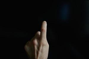 index finger pointing at the screen, black background photo