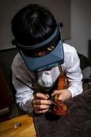 young Chinese violin maker at work in her workshop photo