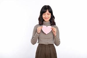 Beautiful young asian woman holding a paper heart while standing against white background. Beautiful young asian woman with paper heart. photo