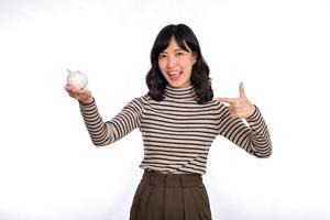 Portrait of young Asian woman casual uniform holding white piggy bank isolated on white background, Financial and bank saving money concept photo