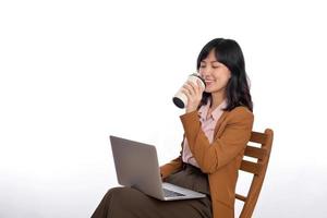 Beautiful young asian businesswoman using computer laptop sitting on white chair and drinking coffee isolate on white background. photo