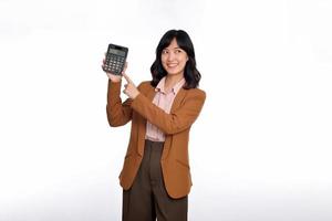 Tax day concept. Asian woman confident smiling holding calculator and finger point device, Portrait happy Asian female isolated on white background, Account and finance counting income photo