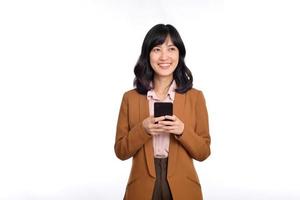 People and technology concept. Smiling asian girl using smartphone, texting on mobile phone, standing against white background photo