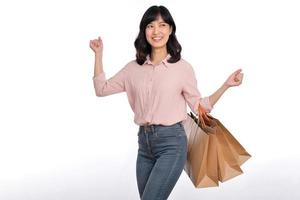 Young happy asian woman with casual shirt and denim jeans holding shopping paper bag isolated on white background photo