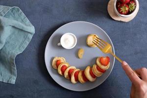 Small pancakes with strawberries in the original serving in the form of a smiley face. Top view. Flat lay photo
