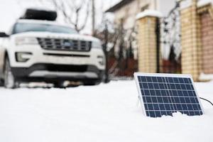 Portable solar panel against SUV car at winter. photo