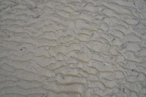 Wavy sand texture due to water waves on the beach photo