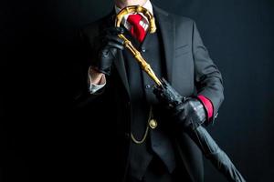 retrato de Caballero en negro traje y rojo Corbata participación paraguas en negro antecedentes. retro Moda y Clásico estilo. foto
