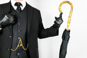 retrato de Caballero en oscuro traje equilibrio un paraguas en su dedo. Clásico estilo y retro moda. foto