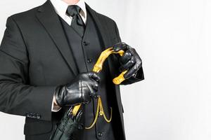 retrato de Caballero en oscuro traje y cuero guantes participación un paraguas en blanco antecedentes. Clásico estilo y retro moda.